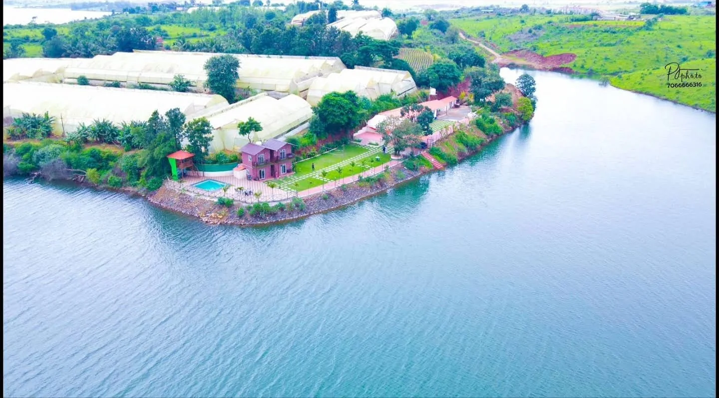 Aerial view of Aandra Lakestay Resort on its lakeside promontory near Pune, showing the pool, lawns and guest buildings