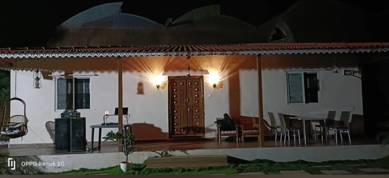 Tile-roofed pavilion lit at night, with a curved shell roof behind, at Aandra Lakestay Resort near Pune