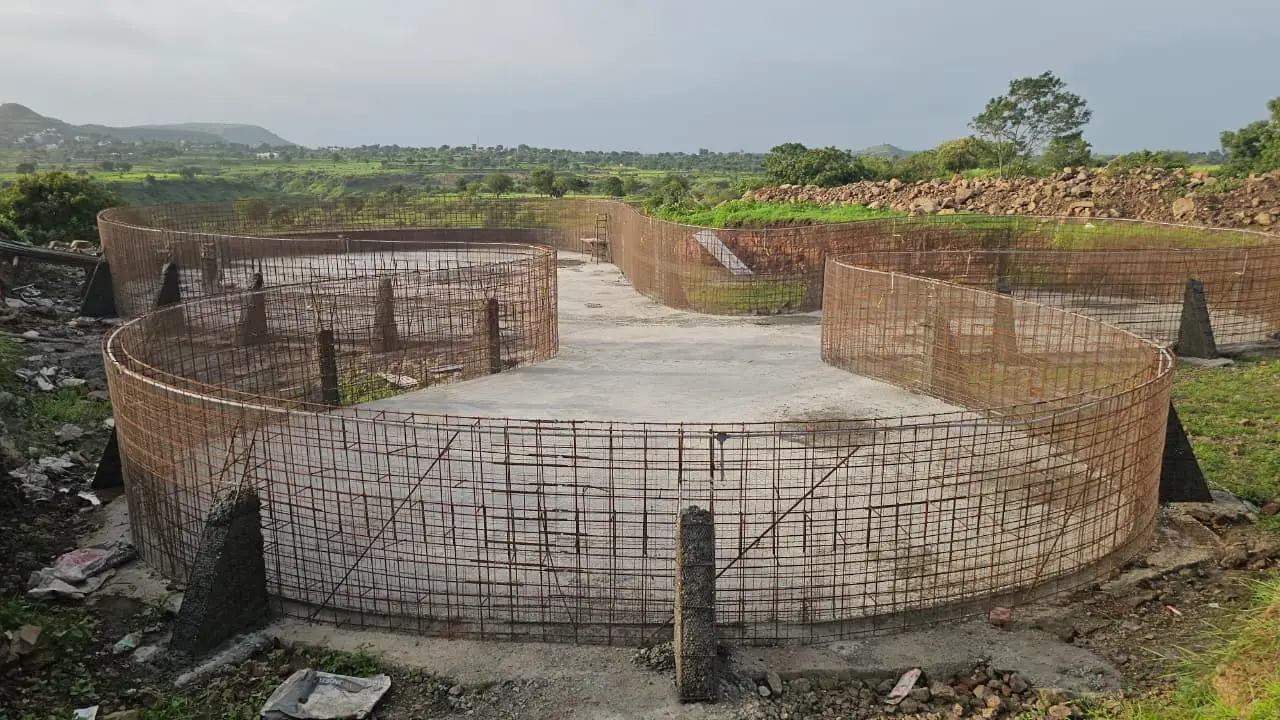 Brahma Valley, Chhatrapati Sambhajinagar — the resort's main 7-lakh-litre swimming pool under construction by PBJ Infra, its curved walls tied out in reinforcement steel over the cast base slab