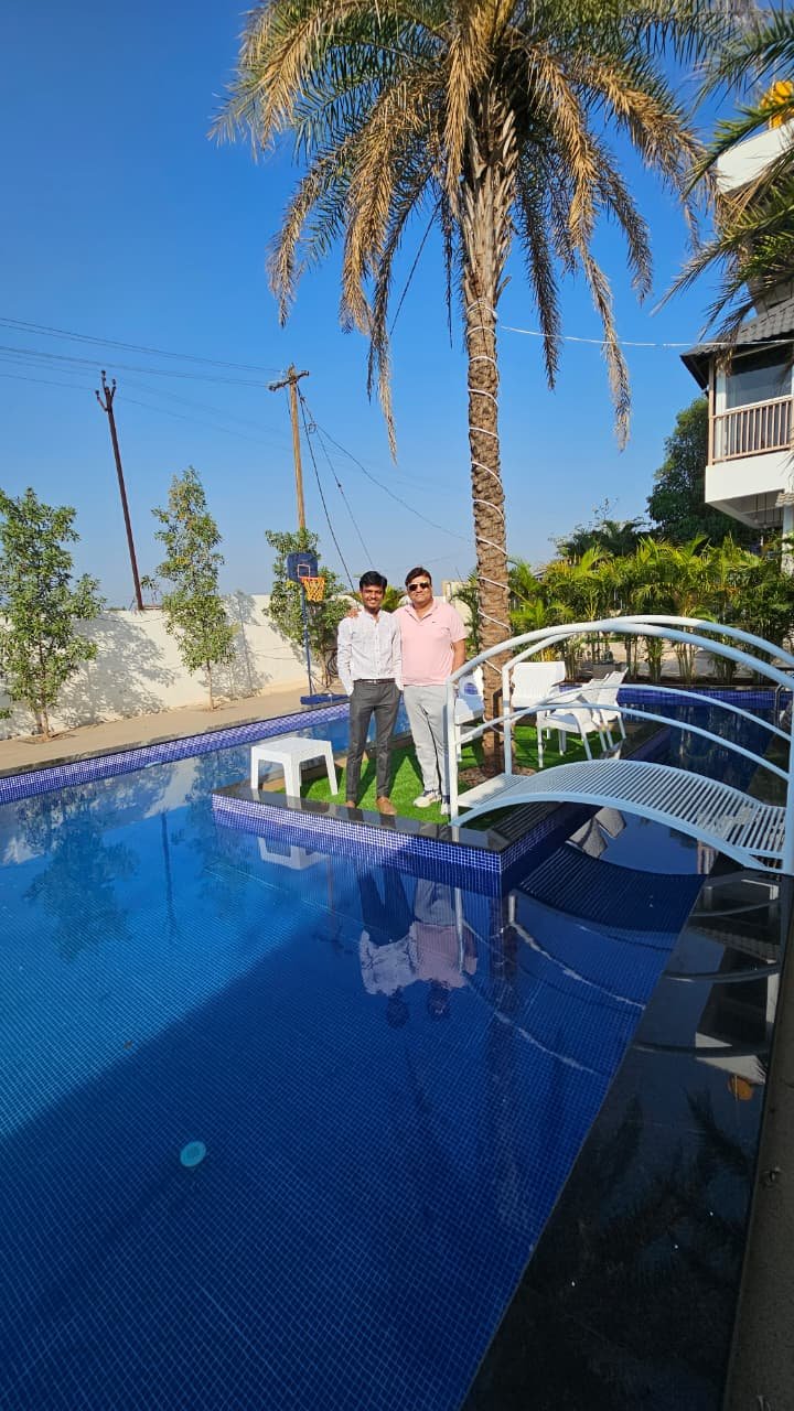 The completed pool at AK Gemak Resort, Kolhapur, with its bridge walkway and blue mosaic tiling, seen from the deck