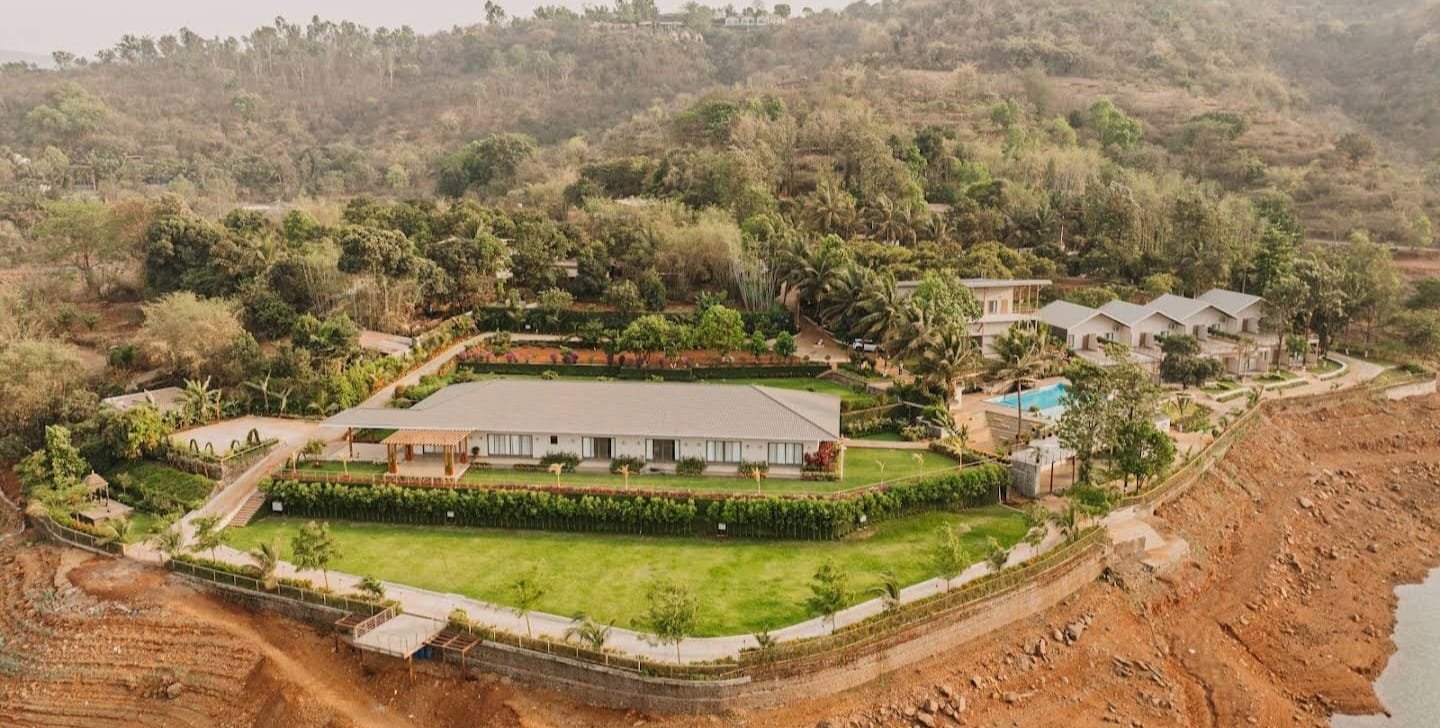Aerial view of Jalashay Resort on a promontory into the Panshet reservoir — main hall, guest block, villa cottages and pool