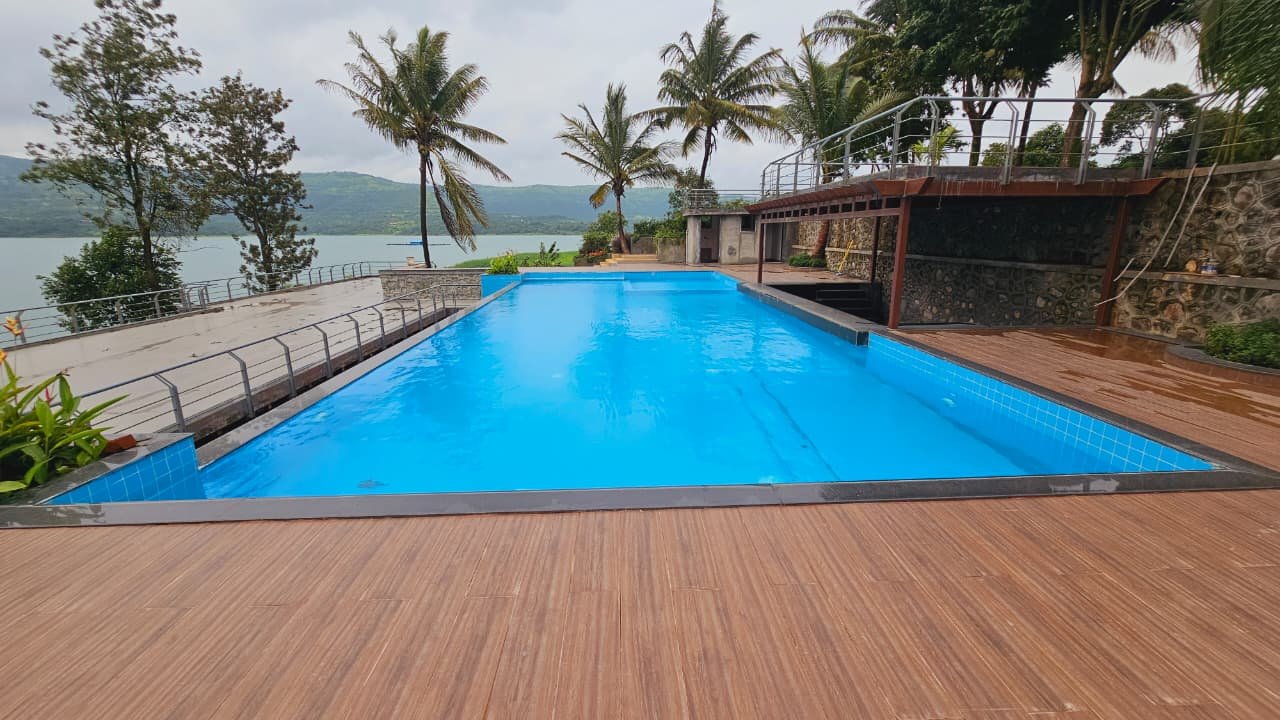 The infinity pool reading level with the Panshet backwaters, framed by coconut palms