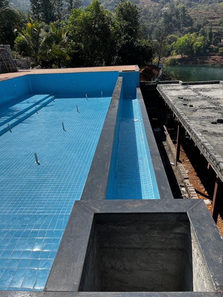 Pool shell, overflow channel and balancing tank under construction on the edge of the reservoir