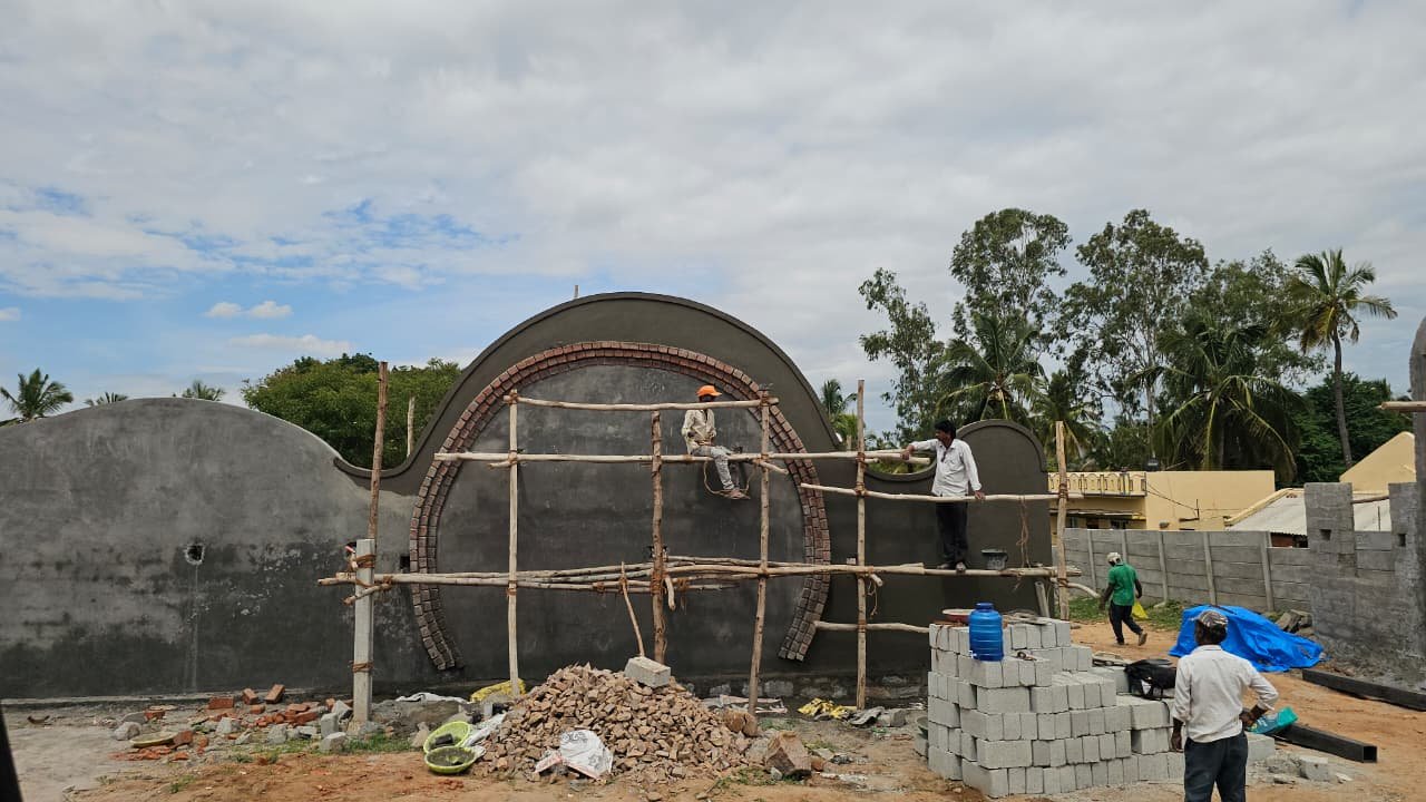 Close view of the circular portal in the Mi Casa wall, ringed with a brick voussoir arch, under construction on bamboo scaffolding