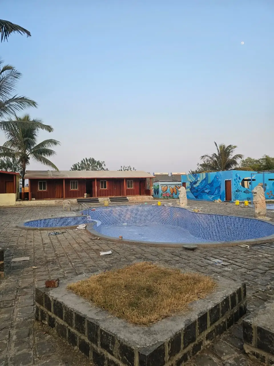 Free-form blue mosaic-tiled resort pool with a separate shallow lobe and paved stone deck at Takawe Resort, Kamshet, built by PBJ Infra