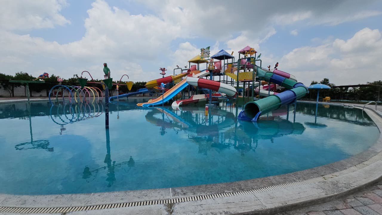 The large curved leisure pool with its central play structure, seen across calm water