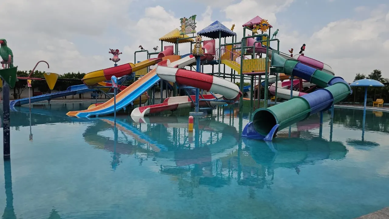 Anandvan Water Park by PBJ Infra in Ahilyanagar, Maharashtra — multi-slide children's play structure mirrored in a still leisure pool